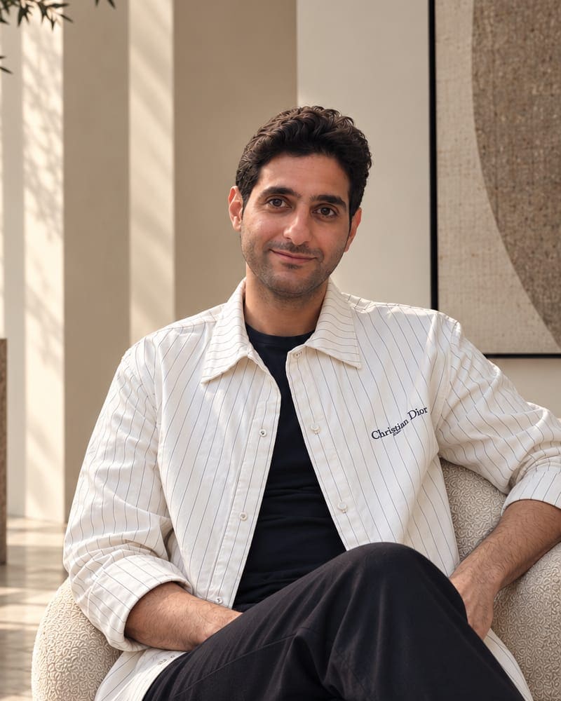 Ahmad seated in a bouclé armchair in a sunlit room